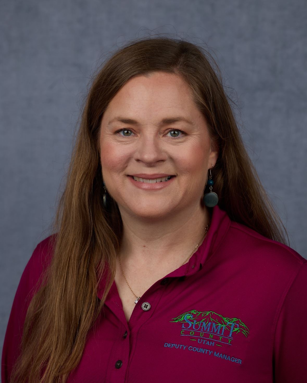 Photo of Janna Young smiling in a purple top with a plain blue background.